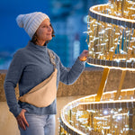 Woman in winter clothing standing next to a large, ornate golden structure.
